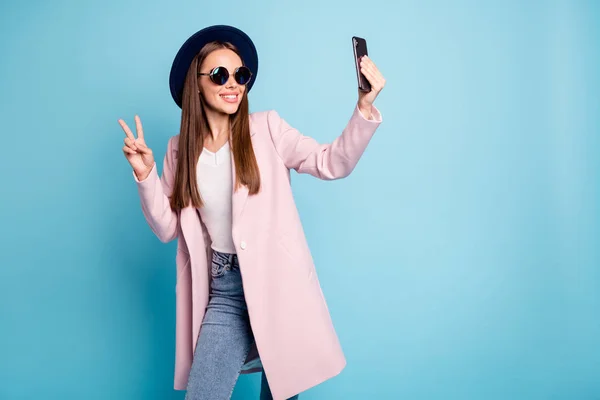 Portrait von niedlichen Content Blog-Mädchen in Brillen Brillen machen V-Sign Selfie macht Spaß tragen rosa stylische Vercoat Topcoat Jeans isoliert über blauem Hintergrund — Stockfoto