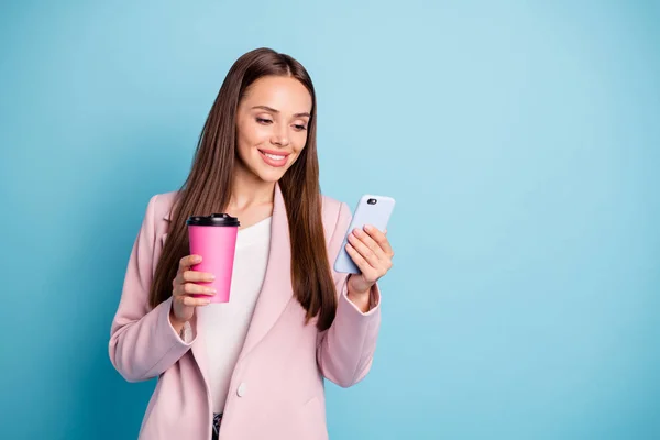 Portrait of charming cheerful lady using her cell phone reading news blogs wearing topcoat isolated over blue color background — Stock Photo, Image