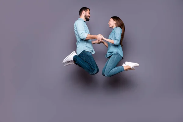 Foto de tamaño completo de los estudiantes románticos alegres sostienen pantalones vaqueros de salto de mano aislados sobre fondo gris — Foto de Stock