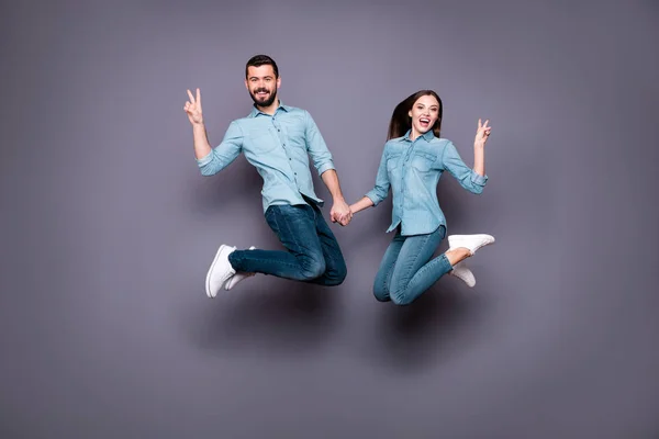 In voller Größe Foto von zwei fröhlichen Menschen springen Make V-Zeichen tragen Jeans isoliert über grauem Hintergrund — Stockfoto