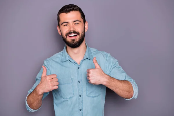 Porträt eines fröhlichen Mannes, der Daumen hoch Werbung trägt Jeans-Hemd isoliert über grauem Hintergrund — Stockfoto