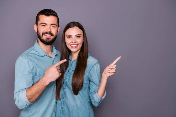 Portret van twee charmante mensen tonen advertenties met zijn haar vingers dragen denim jeans shirt outfit geïsoleerd over grijze achtergrond — Stockfoto