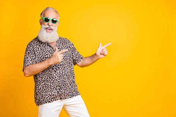 Ritratto di pazzo divertente funky vecchio uomo barbuto con occhiali punto occhiali a copyspace consiglia sconti di vendita indossare camicia stampa leopardo isolato su sfondo giallo — Foto Stock