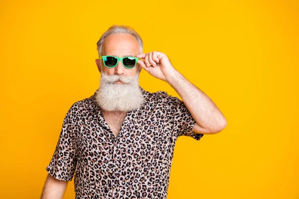 Photo of serious confident old man holding his glasses staring into camera while isolated with yellow background — Stock Photo, Image