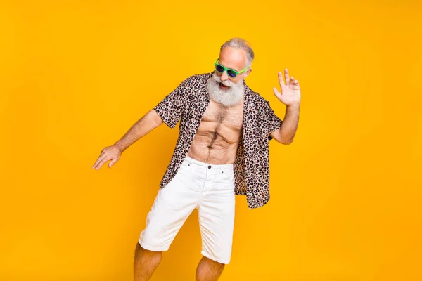 Photo of cheerful still full of strength old man dancing like no one sees him wearing eyewear while isolated with yellow background