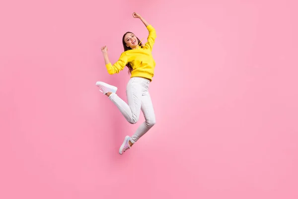 Foto de tamaño corporal de longitud completa de saltar linda encantadora novia atractiva regocijo con algo positivo usando suéter amarillo, mientras que aislado sobre fondo de color pastel rosa —  Fotos de Stock