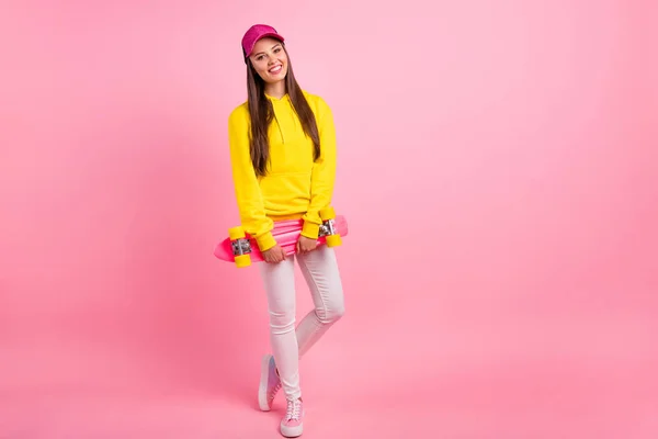 Lunghezza completa dimensioni del corpo foto di attraente alla moda carino allegro bella fidanzata indossa pantaloni maglione giallo tenendo skateboard con le mani isolate su sfondo rosa pastello — Foto Stock