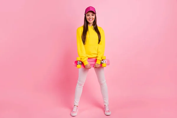 Full length body size photo of cheerful charming cute beautiful sporty girlfriend ready to skateboard wearing yellow sweater isolated over pink pastel color background — Stock Photo, Image