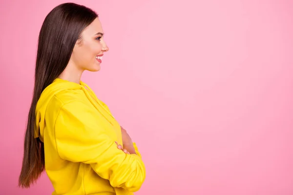 Foto de alegre bonito agradável namorada atraente olhando para algo de pé no esporte desgaste suéter amarelo com os braços cruzados enquanto isolado sobre fundo cor pastel rosa — Fotografia de Stock