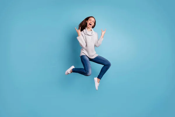 Foto de longitud completa de contenido alegre salto de la juventud mostrar cuernos signos saltar sensación de regocijo tienen fiesta de fin de semana desgaste blanco jersey vaqueros zapatillas aisladas sobre fondo de color azul —  Fotos de Stock