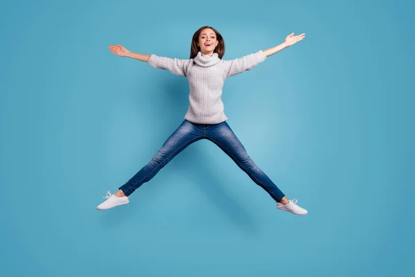 Foto de tamaño completo de linda chica franca saltar como una estrella sentir contenido usar suéter blanco jersey vaqueros jeans zapatillas aisladas sobre fondo de color azul — Foto de Stock