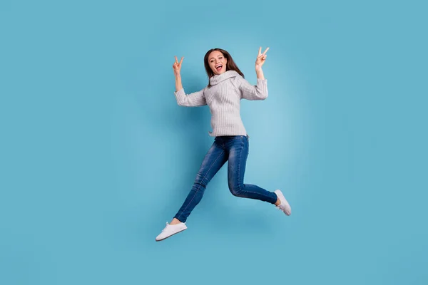 Foto de tamaño completo de contenido loco chica despreocupada salto hacer v-signos grito se siente emocionado regocijo desgaste jersey de punto suéter buen aspecto vaqueros jeans zapatillas aisladas sobre fondo de color azul — Foto de Stock