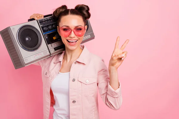 De cerca foto de adolescente alegre haciendo v-signos que sostienen la caja de boom usando chaqueta aislada sobre fondo rosa —  Fotos de Stock