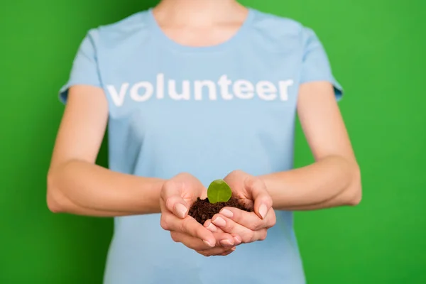 Close-up cropped view portrait of her she kind girl wearing blue t-shirt holding in hands natural soil growing rescue forest isolated over bright vivid shine vibrant green background — Stock Photo, Image