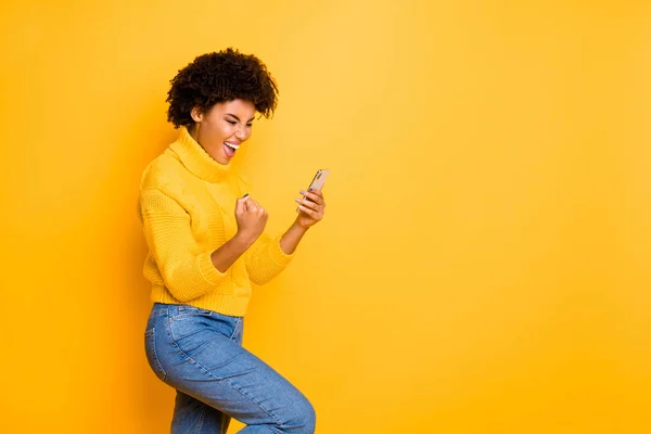 Profile side view portrait of her she nice attractive glad cheerful cheery wavy-haired girl using cell celebrating salary sms message isolated over bright vivid shine vibrant yellow color background — Stock Photo, Image