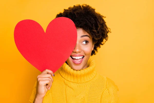 Foto de moda alegre lindo bonito encantador rizado fascinante novia mirando hacia fuera de rojo gran corazón vistiendo jersey amarillo mientras está aislado con fondo de color brillante —  Fotos de Stock