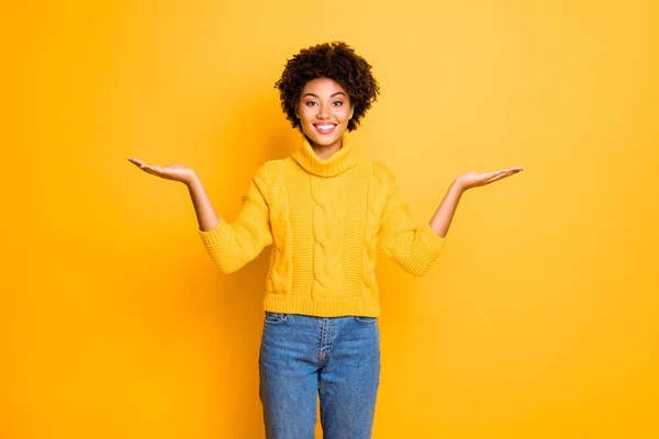 Foto av mörk hud Funny Lady innehar två nya produkter på vapen rådgivning försäljningspriser bära varm Stickad Pullover isolerad gul bakgrund — Stockfoto