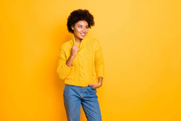 Fotografie tmavé pleti legrační dáma v dobré náladě nosí teplé pletené pulovru a džíny stojící izolované žluté pozadí — Stock fotografie