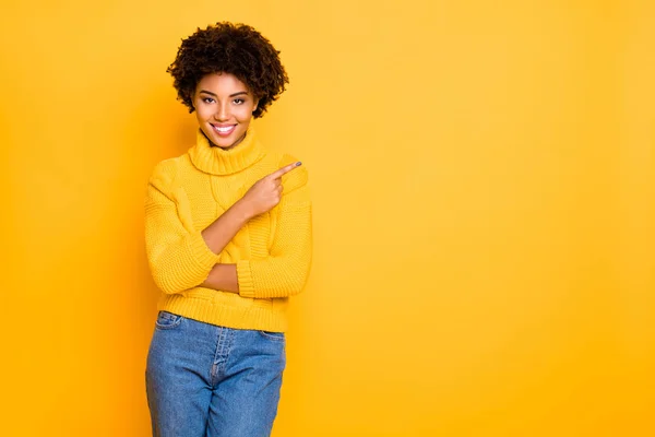 Foto di pelle scura signora indicando dito vuoto spazio usura caldo maglia pullover e jeans isolato sfondo giallo — Foto Stock
