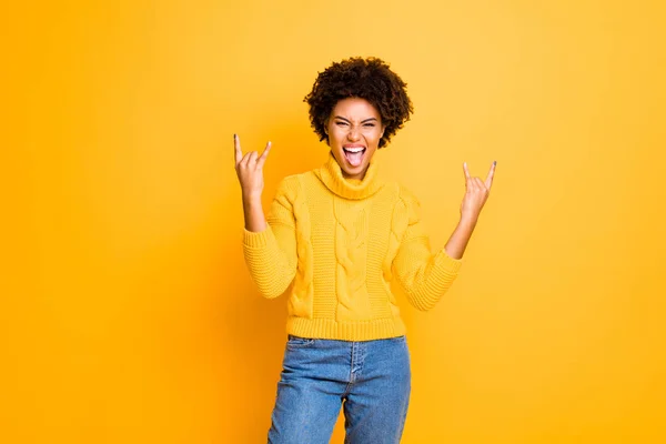 Photo of harsh fan dark skin lady on hard rock concert showing horns symbol wear warm knitted jumper isolated yellow color background — Stock Photo, Image