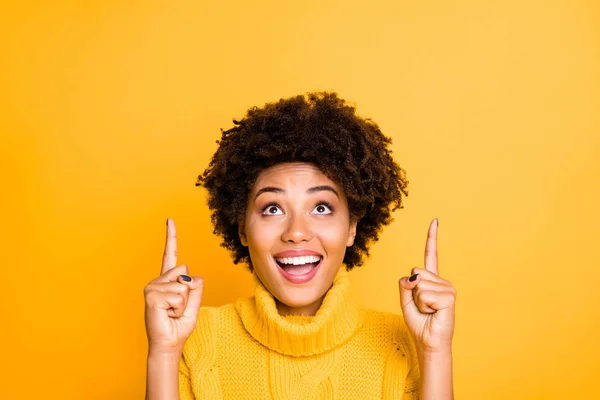 Photo of dark skin pretty lady indicating index fingers up to empty space on cool placard wear warm knitted jumper isolated yellow background — Stock Photo, Image