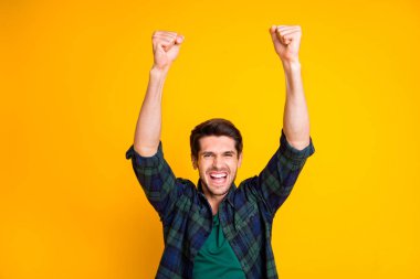 Photo of cool guy watching football game raising fists supporting favorite team wear casual plaid shirt isolated yellow color background clipart
