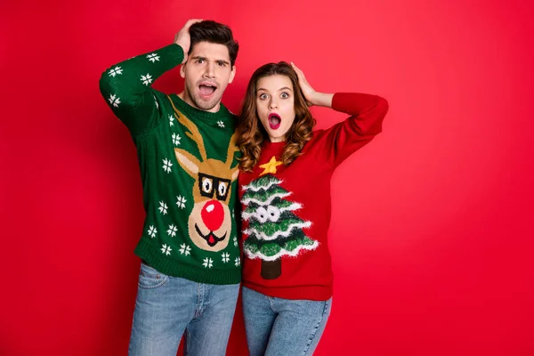 Portret van indruk hipster paar horen ongelooflijk nieuws Scream Wow OMG slijtage herten kerstboom patroon jumper denim jeans geïsoleerd over rode kleur achtergrond — Stockfoto