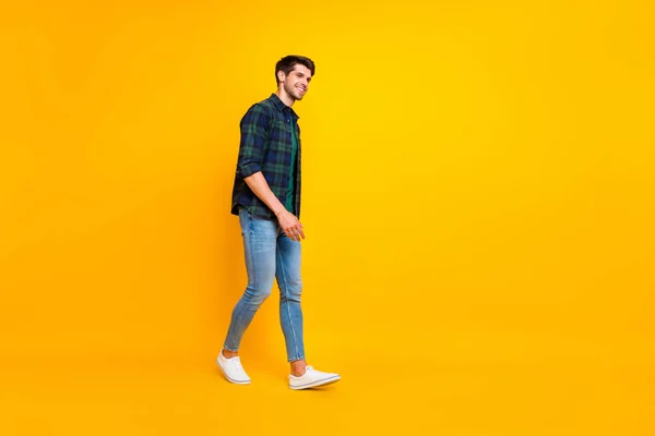 Tamanho do corpo de comprimento total foto de cara atraente alegre caminhando em direção às vendas usando tênis isolado sobre fundo de cor vívida amarelo — Fotografia de Stock