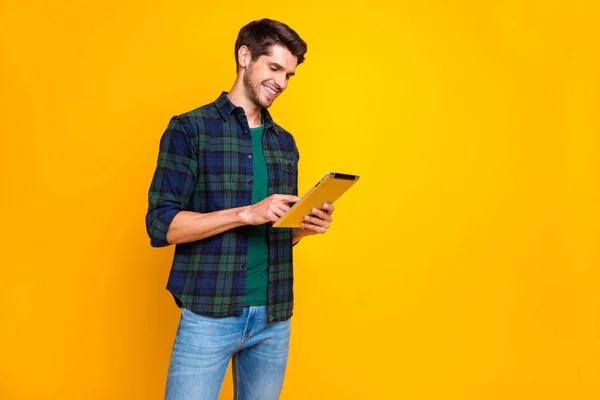 Foto de perfil de un chico guay con lector electrónico en las manos viendo webinar usar camisa a cuadros casual aislado color amarillo fondo — Foto de Stock