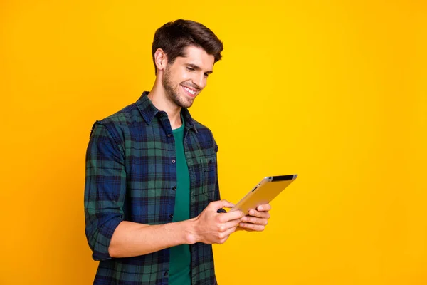 Фото крутого хлопця з електронним читачем в руках, який дивиться онлайн-лекцію, одягнений у шашкову сорочку, ізольований жовтий кольоровий фон — стокове фото