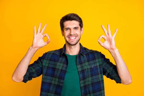 Foto de increíble macho chico mostrando símbolos okey expresando el estado de ánimo positivo desgaste casual camisa a cuadros aislado color amarillo fondo — Foto de Stock