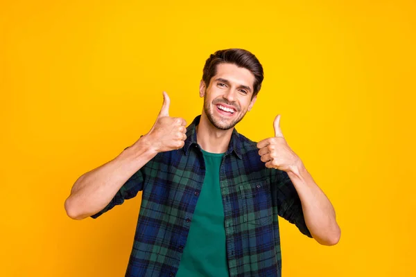 Foto de tipo macho increíble levantando pulgares hacia arriba aprobando la buena calidad de uso del producto casual camisa a cuadros aislado color amarillo fondo —  Fotos de Stock