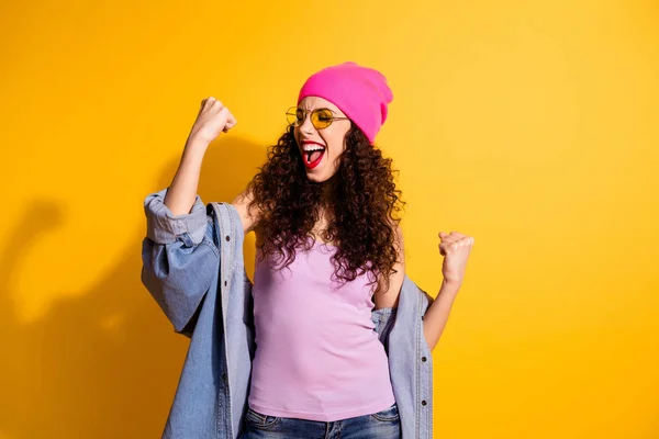 Portret van verheugd positief meisje raise vuisten schreeuwen ja vieren overwinning in competitie slijtage denim jeans jasje roze tank-top geïsoleerd over gele kleur achtergrond — Stockfoto