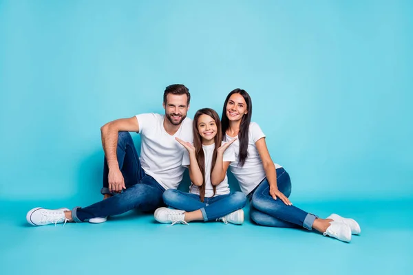 Foto de tamaño completo del cuerpo de la familia sentada en el suelo que le da sonrisas dentales mientras está aislado con fondo azul — Foto de Stock