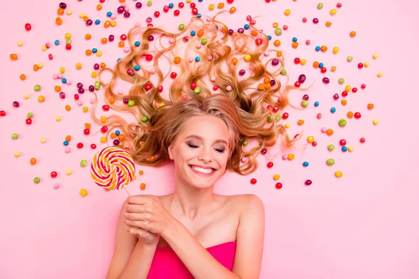 Vertical side profile top above high angle view photo she her lady lying down sweets ideal hair chocolate colored little candies arms hands lolly pop eyes closed imagination isolated pink background — Stock Photo, Image