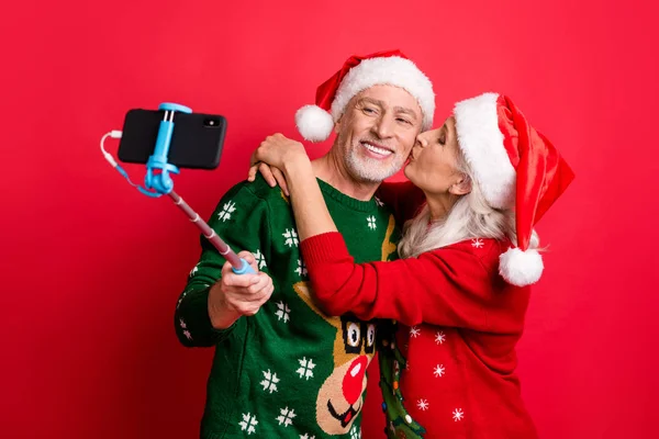 Bloguer le temps concept de médias sociaux. Photo de deux amoureux romantiques aux cheveux blancs et gris rêveurs mariés faisant des photos sur la cellule en utilisant monopode embrassant embrasser dans la joue fond isolé — Photo