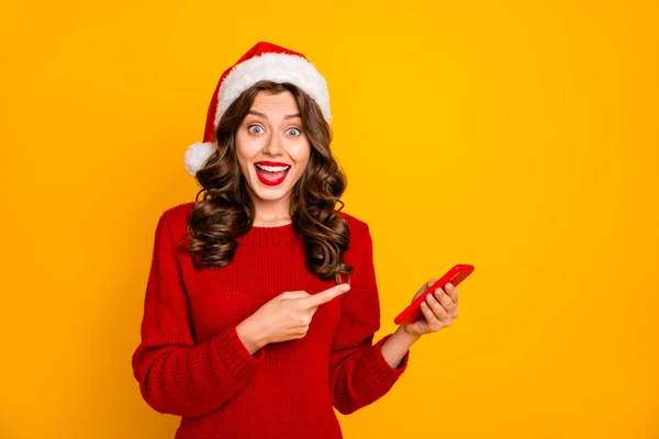 Dame drôle tenant le téléphone avec le prix de vente à la main porter pull tricoté rouge et santa chapeau isolé fond jaune — Photo