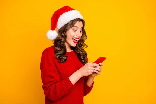Foto van mooie dame houden telefoon in handen slijtage gebreide Pullover en Santa hoed geïsoleerd gele achtergrond — Stockfoto