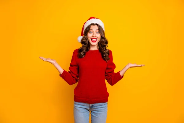 Krásná dáma, která navrhuje novu na otevřeném náručí nosí červený pletený svetr a Santa Hat izolované žluté pozadí — Stock fotografie