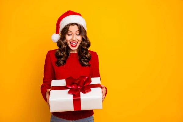 Bella signora in possesso di grande giftbox in armi indossare maglia pullover e cappello di Babbo Natale isolato sfondo giallo — Foto Stock