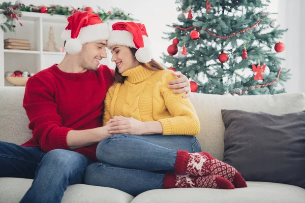 You are my world... Portrait of two romantic people spouses hug feel romance sit on divan in christmas time newyear vacation wear santa claus hat in house with noel decoration ornaments — Stock fotografie