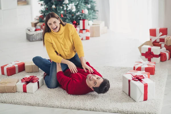 Foto de tamaño completo de divertidos casados funky se divierten tumbados en el suelo riendo disfrutar de las vacaciones de Navidad en casa con la decoración de Navidad ambiente de acebo nuevo año en el interior —  Fotos de Stock