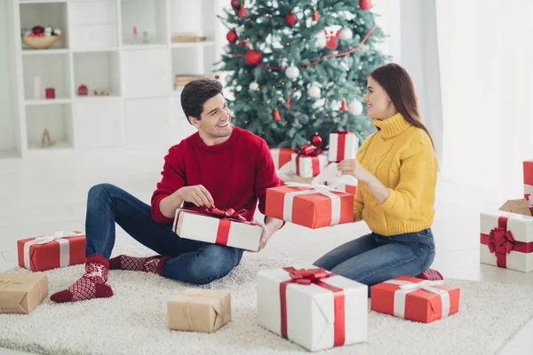 Pełny rozmiar profilu zdjęcie boczne dwóch romantycznych osób trzymać prezent pudełko dostać prezenty od Świętego Mikołaja siedzieć na podłodze w domu z wiecznie zielone drzewo x-mas Noel dekoracji — Zdjęcie stockowe