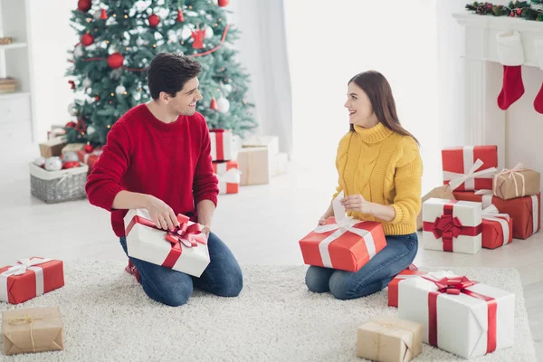 Fotografie ze dvou romantických lidí otevřené dary od Santa Clause si užijí vánoční tradice a sedí na podlaze doma s výzdobou v interiéru x-mas. — Stock fotografie