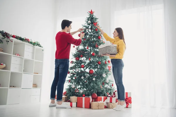 Volledige lengte lage hoek weergave foto van twee romantische mensen versieren CRISTMAS groenblijvende boom hang ballen speelgoed voorbereiden voor Noel viering geniet van x-mas sfeer in huis binnenshuis — Stockfoto