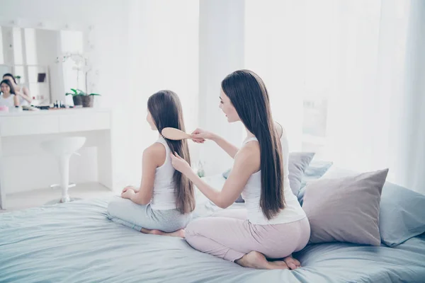 Achterzijde achter achteraanzicht portret van twee mooie mooie aantrekkelijke mooie tedere lieve liefheb je vrolijke zorgvuldige aardige mensen maken kapsel zittend op linnen in licht wit interieur kamer binnenshuis — Stockfoto