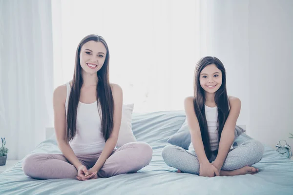 Portret van twee mooie mooie aantrekkelijke mooie vrolijke vrolijke vrouwelijk lieve mensen zittend op bed in Lotus pose vrije tijd weekend vakantie in licht wit interieur huis binnenshuis — Stockfoto