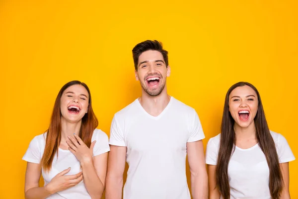 Porträtt av glada kamrater skrattande vidrör bröstet bär vit t-shirt isolerad över gul bakgrund — Stockfoto