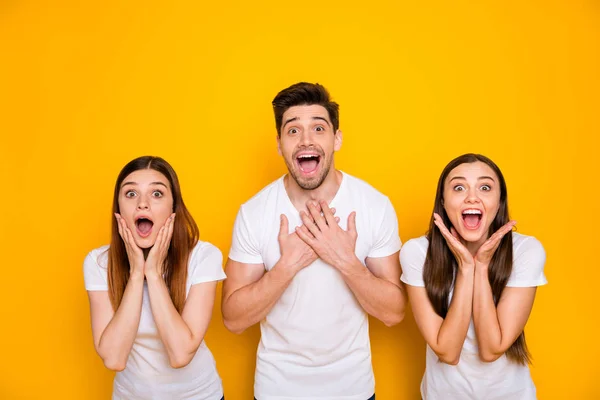 Retrato de três pessoas engraçadas gritando gritando vestindo camiseta branca isolada sobre fundo amarelo — Fotografia de Stock