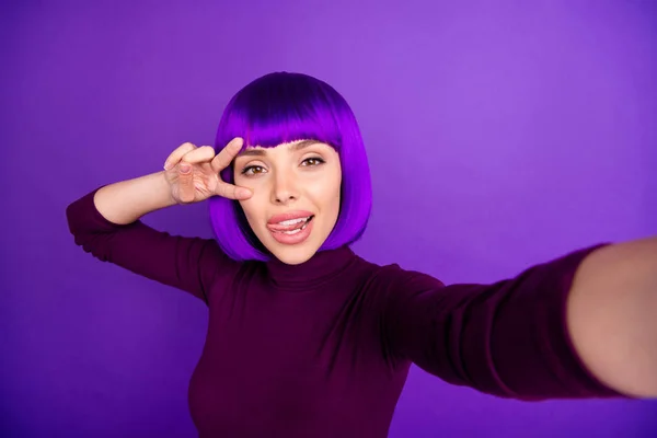 Coqueta señora haciendo fotos de uno mismo pegando lengua fuera de la boca mostrando v-signo de desgaste ropa de moda aislado fondo púrpura —  Fotos de Stock
